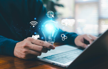 A creative concept image showing a person holding a glowing light bulb beside a laptop, symbolizing innovation, technology, digital ideas, cloud solutions, and modern online connectivity for business
