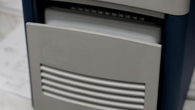 Close up of PCR thermal cycler closing with tray of microtubes in modern laboratory, used for DNA and RNA amplification in molecular diagnostics indoors under lab lighting.