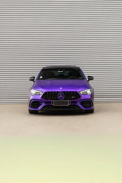 Matte purple Mercedes AMG CLA 45s front view, Performance coupe parked against metal shutter background