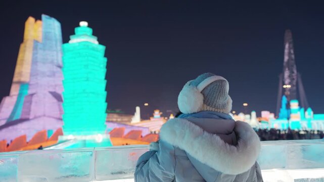 Young happy female tourist enjoying at ice and snow world festival at night in Harbin, China