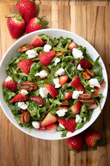Strawberry Salad in a white bowl on a wooden cutting board