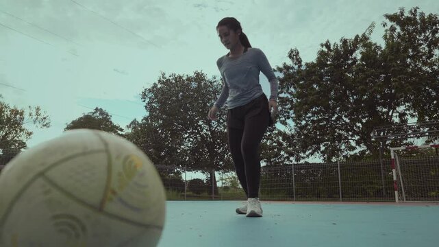 Asian girl playing futsal football outdoor.