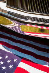 An American flag being reflected on a car bumper - vertical