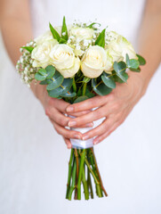 Hands holding a white rose bridal bouquet on white background