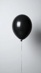 Obraz premium A singular, spherical black balloon, tethered by a thin string, floats in front of a plain white background, capturing a clean and minimalistic aesthetic