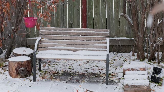 Snow falling on an empty bench on a wintry day