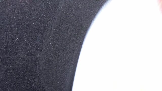 Close up polishing scuffs out of dark grey car paint with white microfiber polishing pad