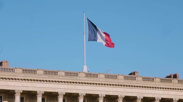 The French tricolore flag waving in slow motion above the H&ocirc;tel de la Marine, Paris, under a vivid blue sky