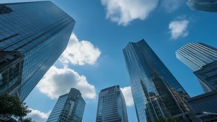 Dynamic upward shot of modern skyscrapers reflecting blue sky and clouds, perfect for corporate growth and success, urban development, and architecture - Powered by Adobe