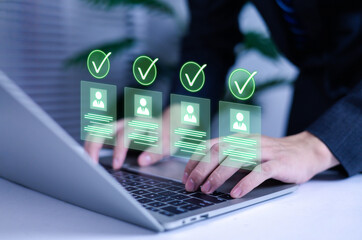 Businessman using laptop for digital recruitment with holographic candidate profiles and green check marks. Concept of online hiring, HR technology, AI recruitment, and human resource management.