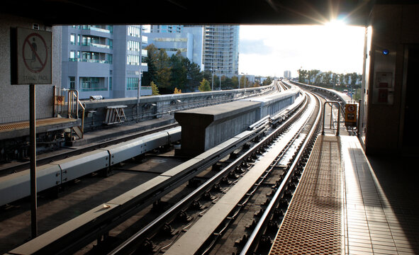 Elevated train tracks in sunlight at urban station - Powered by Adobe