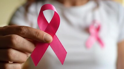 Woman holding a pink ribbon for breast cancer awareness - Powered by Adobe
