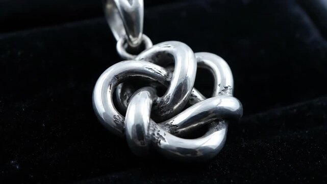 Close up view of silver knot pendant on black background