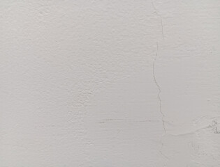 Abstract texture of minor vertical hairline cracks in a white wall.