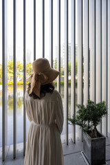 Woman in a Hat Behind a Modern Vertical Window with City View