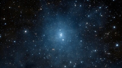 A bright dense star cluster glows in the deep blue expanse of space surrounded by faint nebulous clouds