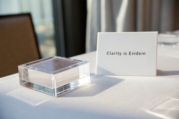 Clear acrylic block beside white card with text Clarity is Evident