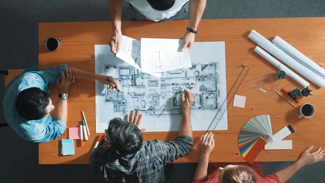 Time lapse of smart architect engineer team talking about project plan while manager walking at meeting table and start working and analyze building construction and looking at blueprint. Symposium. - Powered by Adobe