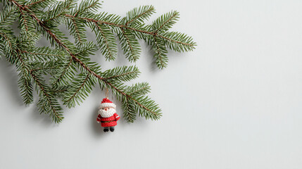 small Santa Claus ornament hangs from green pine branch against plain white background, creating festive and minimalist holiday scene