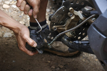 Close up of biker hand using hex key for bicycle repair on trail. person shows intense...