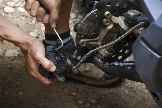 Close up of biker hand using hex key for bicycle repair on trail. person shows intense concentration while performing maintenance on bike mechanical part - Powered by Adobe