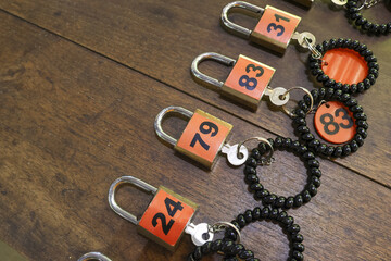 Neat row of orange padlocks with keys and numbers sits on wood background. This organized system of locks provides security and privacy for locker room at gym or spa