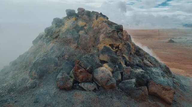Volcanic rock fumarole releasing hot steam and sulfurous gas in a geothermal area in Iceland