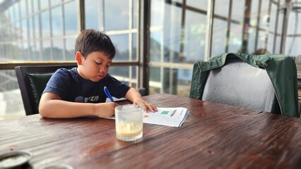 Asian boy is studying seriously. His dad teach him  doing  worksheet.
