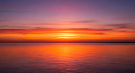 The sun sets over the ocean, painting the sky with vibrant hues of orange and purple, creating a serene and breathtaking scene