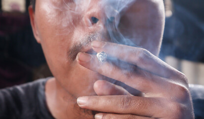 Asian man smoking a cigarette. Cigarette smoke spread.