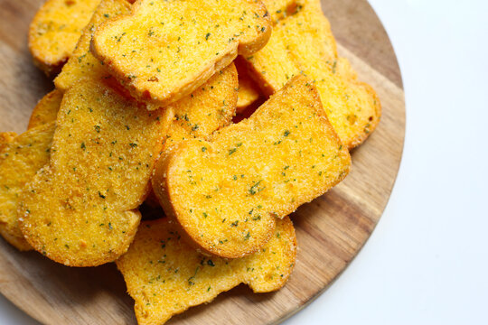 Crispy garlic bread slices on wooden cutting board