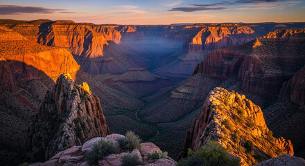 Panoramic view of the grand canyon at sunrise, showcasing the vast canyon walls, rock formations, and the play of light and shadow in the early morning
