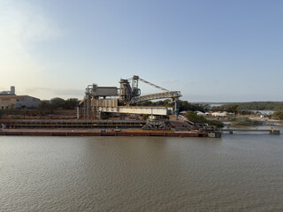 Fototapeta premium Modern port terminal unloading ore, bauxite, and petroleum coke with massive screw unloader aluminum production. heavy machinery, cargo terminal, industrial equipment, seaport, maritime logistics 88