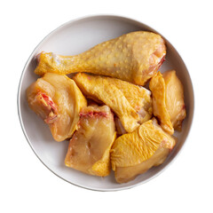 A top down view of a white bowl filled with raw uncooked chicken pieces including drumsticks and thighs on a black background