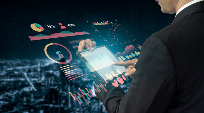 A business professional in a suit engages with a tablet displaying colorful graphs and charts, set against a city skyline at night, emphasizing data-driven decision-making. Impute - Powered by Adobe