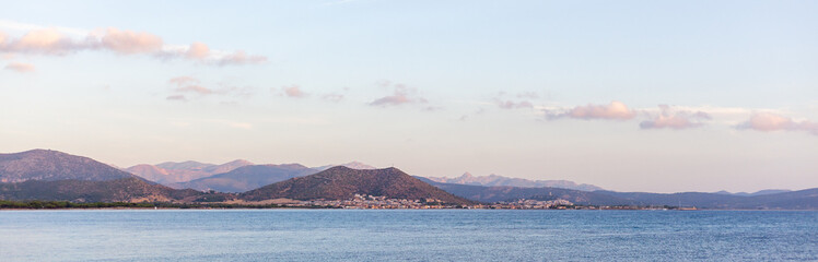 Fototapeta premium Scenic view of rolling hills along the Sardinia coast with a tranquil sea and clear blue sky.