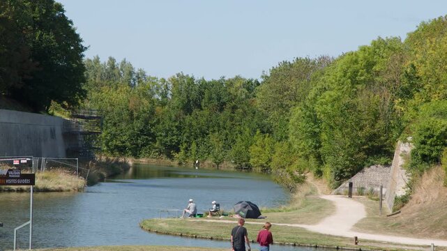 People Walking and Fishing Along River in Dunkirk Park