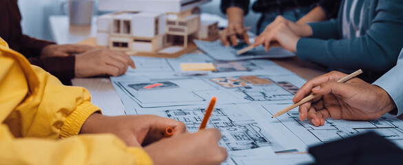 A dynamic collaborative design session where architects and clients engage in sketching blueprints and models for innovative building projects, showcasing teamwork. SACTR
