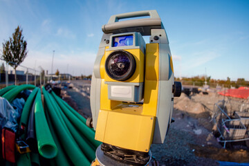 Close-up of surveying equipment total station EDM set up at a construction site during sunset