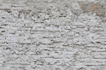 Full frame background of an old white-washed brick wall texture with rough, deteriorating stucco