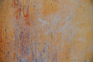 Textured orange rusty metal wall with colorful streaks and patterns from various activities