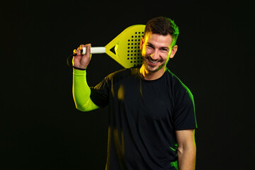 Smiling man holding a paddle with a sporty look in a dramatic lighting setup