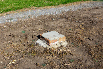 Brick column foundation near gravel driveway and green lawn on residential construction site