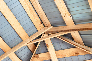 Wooden trusses installed under metal roofing provide structural support for a buildings roof system