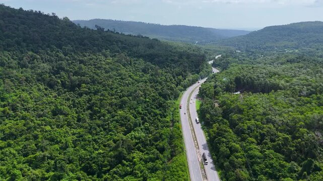 Drone footage of the aerial view of a winding road cutting through lush green forest. Scenic highway number 304 in Thailand links the Bangkok area to Nakhon Ratchasima in the northeastern region