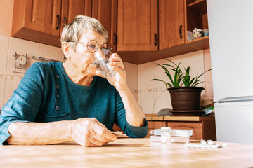 An elderly woman takes a large number of medications daily. Chronic disease treatment, aging, health problems, dementia and loneliness, home treatment, regular pill intake