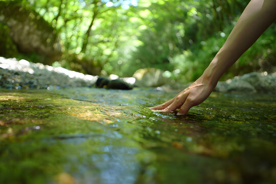 Gentle Touch Hand Caressing a Clear Stream in Nature's Embrace - Powered by Adobe