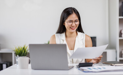 Asian Female Using Laptop Computer Focused Woman Working with Documents at Desk
