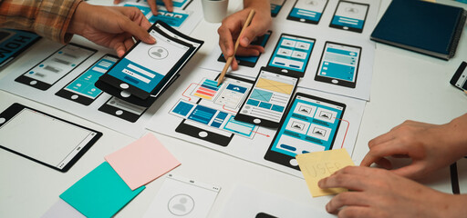 Team Collaborating on Mobile App Design with Wireframes and Prototypes on Table, Focus on Creative Process and User Experience Development SACTR