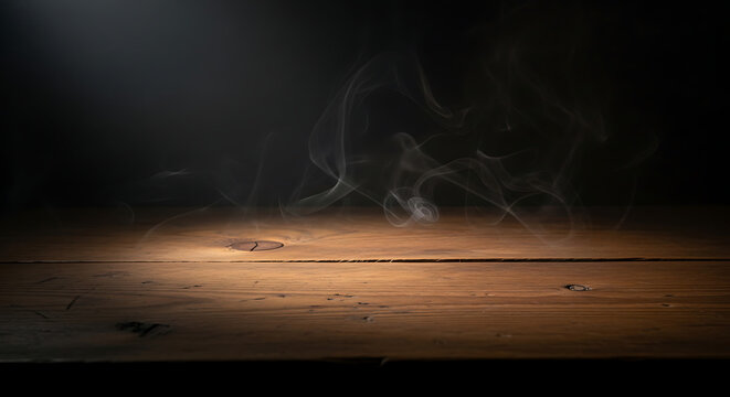 Dramatic image of wispy white smoke swirling above textured, rustic wooden planks against a dark background